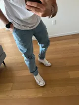 Pantalón de jean celeste oversize, de corte recto y tiro medio, con detalles de roturas y desgaste en las rodillas.