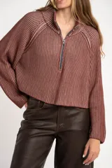 Sweater marrón de punto acanalado, con cuello alto, cierre frontal parcial con cremallera y manga larga.