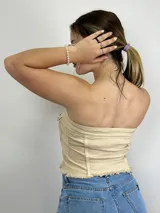 Top strapless color beige con botones plateados al frente y dos bolsillos pequeños.