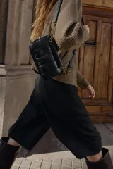 Bandolera mini de diseño acolchado con pespuntes verticales. Cuenta con doble compartimento, uno con cierre imantado y otro con cremallera, además de un bolsillo frontal con cierre imantado. Incluye asa regulable con detalle de cadena metálica.