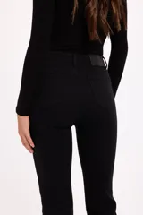 Jean de corte bootcut con tiro medio, confeccionado en denim con elasticidad. Presenta un ajuste entallado en cadera y muslos, con una leve apertura desde la rodilla hacia el ruedo.