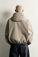 Cazadora de denim de algodón color negro con efecto lavado, de corte relaxed fit, manga larga y capucha. Cuenta con cierre frontal de cremallera, bolsillos frontales tipo canguro y acabados con elástico en puños y cintura.