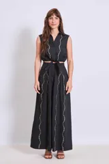 Pantalón negro de tiro alto y corte palazzo, con detalle de strass plateado en forma de ondas verticales.
