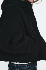 Chaqueta acolchada de corte corto con cuello subido y capucha. Presenta cierre frontal con cremallera termosellada y solapa con botones a presión, bolsillos laterales con cierre, mangas largas con puños elásticos y bajo ajustable con cordones.