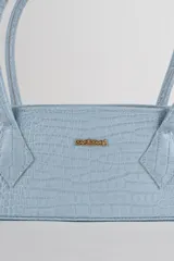 Cartera tipo baguette color negro con textura efecto cocodrilo, diseño alargado, doble asa de mano y cierre superior.
