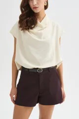 Blusa de poliéster color marfil, de corte holgado, sin mangas y con cuello buche drapeado.