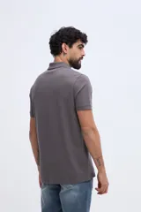 Remera polo verde militar de algodón pima, con cuello y puños acanalados, cierre frontal de tres botones y pequeño bordado de ave en el pecho.