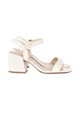 Sandalias de taco ancho alto confeccionadas en cuero color off-white, con tira delantera simple, tira en el empeine y correa al tobillo con hebilla forrada.