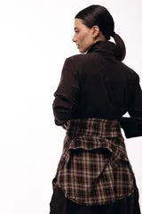 Vestido camisero de color marrón oscuro, con cuello clásico, cierre frontal de botones y mangas largas. Presenta un diseño de corte recto y largo midi.