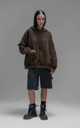 Hoodie de corte oversize y largo crop, confeccionado en algodón con efecto de desgaste y color óxido. Presenta costuras expuestas, detalles de roturas en los bordes y bolsillo frontal tipo canguro.
