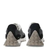 Championes urbanos New Balance modelo 327, con diseño retro inspirado en los años 70. Presentan una combinación de paneles de gamuza negra y malla gris, con el logo 'N' sobredimensionado en color gris claro en el lateral. Incluyen cordones blancos, entresuela de espuma blanca y suela de goma con relieve extendido hacia el talón.