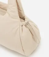 Cartera tipo shopper de gran tamaño, confeccionada en poliéster con acabado acolchado y textura lisa. Presenta un diseño de trapecio invertido con correas integradas para llevar al hombro y cierre superior con cremallera.