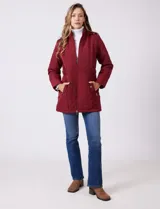 Campera capitoneada de largo midi en color bordó, con diseño de rombos en el cuerpo y mangas, y costuras diagonales en los laterales. Cuenta con cierre frontal, capucha desmontable con interior suave y panel entallado en la cintura.