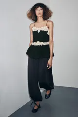 Pantalón bombacho de tiro alto con cintura elástica, confeccionado en tejido fluido con acabado satinado. Presenta un diseño holgado con bajo acabado en puño elástico y detalle de lazada ajustable.