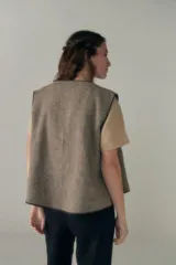 Chaleco corto de lana fina sin teñir, con diseño de solapa cruzada y terminaciones envivadas. Es una prenda reversible, liviana y versátil, ideal para uso diario.