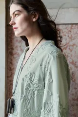 Collar de cordón fino con nudo ajustable. Presenta colgantes combinados que incluyen una pieza metálica, una piedra decorativa y un pequeño monedero circular de piel con cierre.