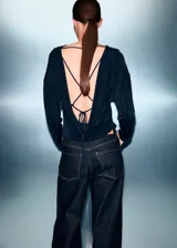 Top de manga larga en color negro, con diseño recto y cuello drapeado. Confeccionado en tejido fluido con acabado ligeramente satinado.