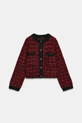 Chaqueta de punto con textura y estructura de tweed, en combinación de rojo y negro. Cuenta con cuello redondo, manga larga, bolsillos delanteros de plastrón y cierre frontal con botones metálicos dorados.