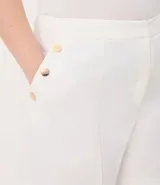 Bermuda de crepé color blanco, de corte holgado y tiro alto, con pliegues frontales y bolsillos laterales con detalle de botones. Confeccionada en poliéster y elastano.