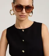 Chaleco negro de sastrería con cuello redondo, cierre frontal con botones dorados y bajo estructurado con recortes anatómicos.