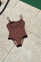 Traje de baño entero color marrón oscuro, con escote en U, tirantes finos ajustables y corte bajo el busto.