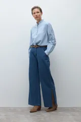 Camisa blanca de manga larga con cuello alto fruncido y bordados calados en el pecho y los hombros.
