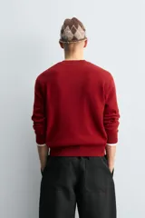 Jersey de lana con cuello en pico y manga larga, con diseño de rombos en tonos rojo, azul marino y gris. Presenta terminaciones en rib en puños y cintura.