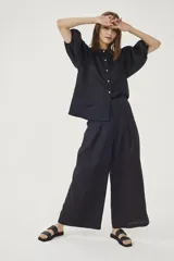 Pantalón culotte negro de lino orgánico, con cintura alta, diseño plisado y bolsillos laterales.