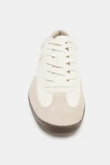 Zapatillas deportivas de mujer, estilo retro de bajo perfil, en tonos blanco hueso y beige claro. Presentan texturas mixtas en el cuerpo (piel granulada y gamuza) y un detalle en el talón de material rojo con textura de cocodrilo. La suela es de goma marrón oscura.