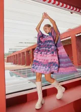 Poncho tejido con cuello alto y aberturas laterales, con diseño geométrico multicolor en tonos rosa, azul y violeta.