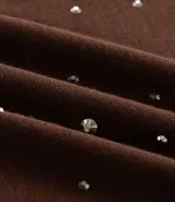 Remera de malla color tostado con cuello redondo, mangas cortas y aplicación de strass salpicado en toda la prenda.