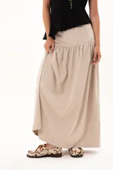 Pollera larga de corte evasé en color arena, con detalle de costura horizontal y frunces en la parte inferior que le otorgan volumen y movimiento.