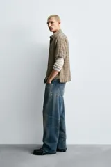 Camisa de algodón con textura arrugada, corte relaxed fit, color beige con patrón de cuadros en tonos marrones y negros. Posee cuello bowling y manga corta.