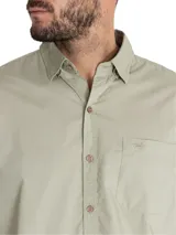 Camisa manga larga color verde oliva, confeccionada en popelina 100% algodón orgánico. Cuenta con cuello camisero, cierre frontal con botones de madera, bolsillo en el pecho con logo bordado y mangas ajustables con botones.