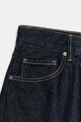 Bermuda baggy de denim azul oscuro con tiro medio, trabillas, cinco bolsillos y costuras en contraste. Cierre frontal con cremallera y botón metálico.