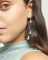 Pendientes colgantes con base de bola plateada, tiras de cuero negro formando un doble lazo y detalles de bolas plateadas en el interior y en la parte inferior.