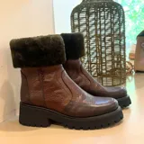 Bota de cuero vacuno con caña media, cuello con corderito sintético y suela de goma tipo track con plataforma.