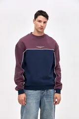 Buzo de cuello redondo en felpa con friza, de calce relajado. Presenta un diseño de bloques de color en azul marino y bordó, con detalles de vivos en color blanco que recorren el cuerpo y las mangas. Incluye un pequeño estampado con el logo de la marca en el pecho.