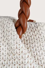 Bolsa mini de textura tejida en color beige, con manijas superiores trenzadas en color marrón y correa de cadena metálica entrelazada. Incluye un detalle de etiqueta colgante en cuero sintético marrón.
