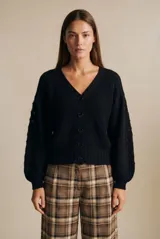 Cardigan negro de algodón con cuello en V, cierre frontal de botones y mangas largas con textura calada. Presenta puños y ruedo acanalados.