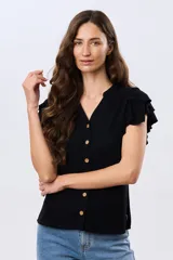 Camisa de lino y viscosa color beige, con cuello mao, escote en V y botones frontales de madera. Presenta mangas cortas con volados delicados.