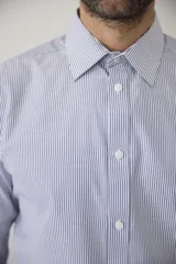 Camisa de vestir blanca de manga larga, con cuello clásico y cierre frontal de botones. Presenta un corte entallado que se adapta a la silueta.