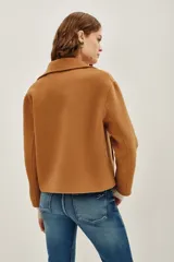 Tapado corto de paño en color tostado, con diseño de doble abotonadura, cuello solapa y mangas largas.