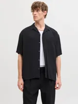 Camisa negra de manga corta con cuello cubano y cierre frontal con botones.