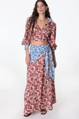 Falda larga celeste con finas rayas verticales blancas, corte evasé y detalle de nudo drapeado en la cintura.