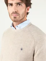 Sweater de lana merino color camel, de cuello redondo, mangas largas y diseño clásico, con pequeño logo bordado en el pecho.