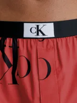 Boxer de algodón con estampado repetido del logo 'CK' en negro sobre fondo rojo. Cintura elástica negra con el logo 'Calvin Klein' en blanco.