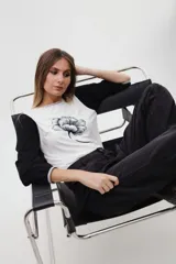 Remera de algodón con cuerpo blanco y estampado de flor de ginkgo en negro. Presenta mangas largas amplias de corte bombé en color negro con textura acanalada, y detalles de ribetes en gris melange en el cuello y los puños.