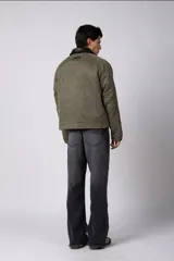 Chaqueta de estilo militar color verde oliva, confeccionada en gabardina resistente. Presenta cuello camisero en contraste color negro, cierre frontal con cremallera, dos bolsillos frontales tipo cargo con solapa y ajuste relajado.