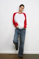 Camiseta de manga larga con diseño ranglan, cuerpo en color blanco y mangas en color rojo. Presenta cuello redondo y bajo recto.